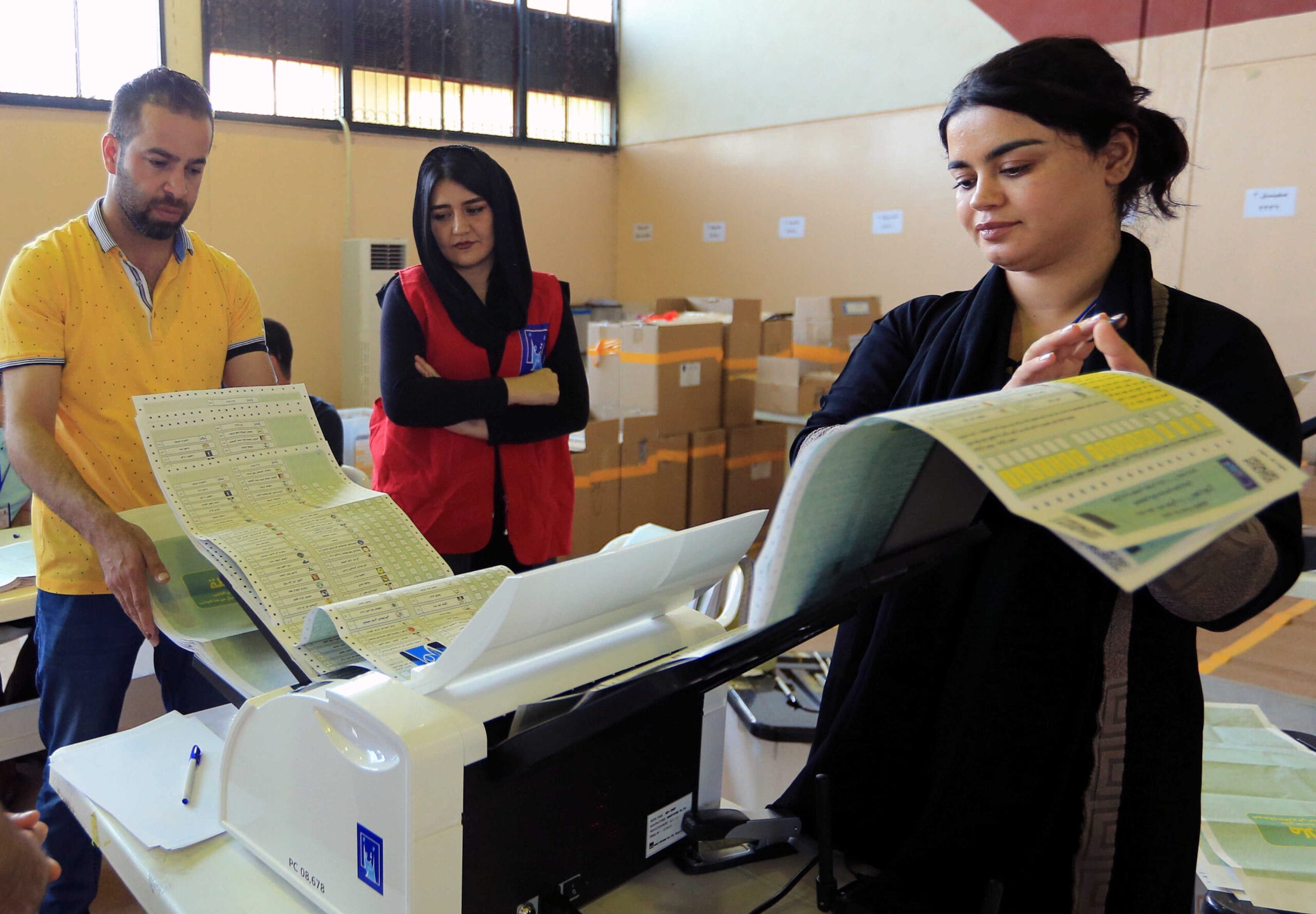 Employees of the Iraqi Independent High Electoral Commission check electronic counting device at a warehouse in Dohuk